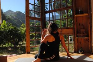 a woman sitting in a room looking out of a window at Hostal Casa Amaya in Vallehermoso