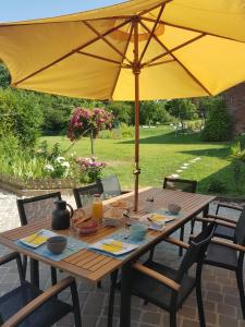 a wooden table with an umbrella on a patio at LA CLER'HIER in Clérey