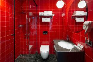 a red tiled bathroom with a toilet and a sink at Zemeli Boutique Hotel by DNT Group in Tbilisi City