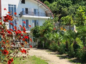 una casa bianca con fiori rossi davanti di Sanni Guest House a Kvariati