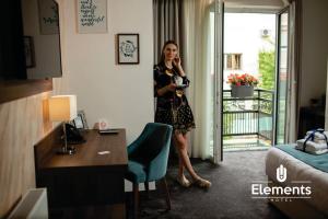 Hotel Elements في نوفي بازار: امرأة تقف في غرفة في الفندق تتحدث على الهاتف