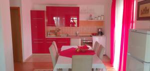 a kitchen with red cabinets and a table with chairs at Filip Apartment in Zadar