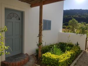 a front door of a white house with flowers at Matjesfontein Estate Keurbooms Chalet in Plettenberg Bay