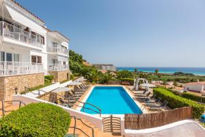a villa with a swimming pool and the ocean at Apartamentos Sunsets in Son Bou