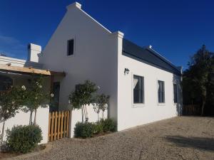 una casa blanca con una valla delante en Matjesfontein Estate Keurbooms Chalet en Plettenberg Bay