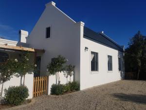 a white house with a fence in front of it at Matjesfontein Estate Keurbooms Chalet in Plettenberg Bay