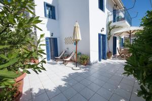 a courtyard of a house with chairs and an umbrella at Aquarella-stylish veranda apartment in centre of Poros town in Poros