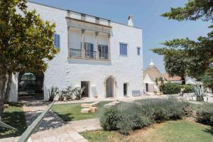 a white house with blue windows and a yard at Relais Masseria Villa Cenci in Cisternino