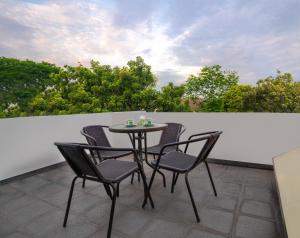 a table and chairs on a balcony with trees at LeGreen Suite Tebet in Jakarta
