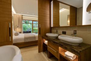 
a hotel room with two sinks and a large mirror at Savoy Seychelles Resort & Spa in Beau Vallon
