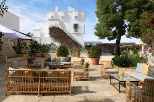 a patio with chairs and tables and a building at Rocco Forte Masseria Torre Maizza in Savelletri di Fasano