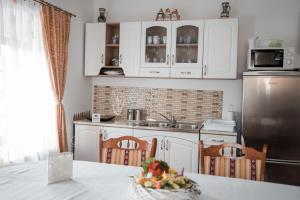 a kitchen with white cabinets and a sink and a table at Muskatli Panzio Sic in Sic +46 photos