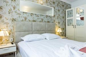 a bedroom with a white bed and floral wallpaper at Sweet Homes Apartments in Sunny Beach
