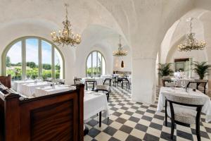 un restaurant avec des tables, des chaises et des lustres blancs dans l'établissement Rocco Forte Masseria Torre Maizza, à Savelletri di Fasano