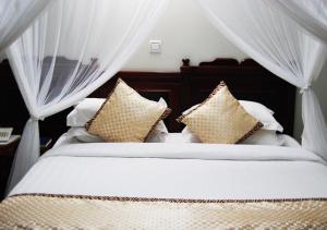 1 dormitorio con 2 camas, cortinas y almohadas en Mc-Elly's Hotel, en Arusha