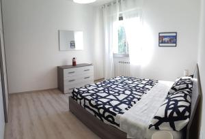a bedroom with a bed and a dresser and a window at Appartamento Sette Lecci in Lido di Camaiore