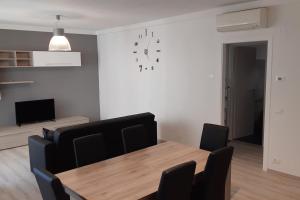 a dining room with a table and a clock on the wall at Appartamento Sette Lecci in Lido di Camaiore