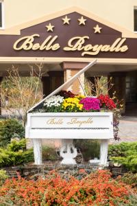 a white piano in front of a building with flowers at Belle Royalle in Lisarnya