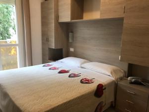 Un dormitorio con una cama con zapatos rojos. en Hotel Villa Enea, en Cattolica
