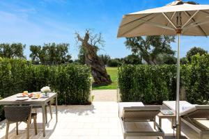 a patio with an umbrella and a table and chairs at Rocco Forte Masseria Torre Maizza in Savelletri di Fasano