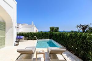 a swimming pool with two lounge chairs next to a house at Rocco Forte Masseria Torre Maizza in Savelletri di Fasano