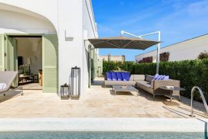 a patio with a couch and an umbrella at Rocco Forte Masseria Torre Maizza in Savelletri di Fasano