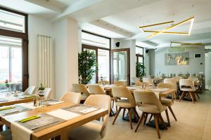 a restaurant with wooden tables and chairs and windows at Hotel Manor in Mamaia Sat/Năvodari