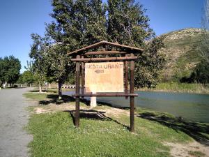 ein Schild im Gras neben einem Wasserkörper in der Unterkunft Adosado, cerca de Valencia en zona de montaña y playa fluvial in Valencia