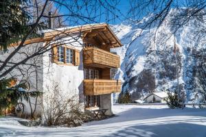 a log cabin in the snow with a snow covered mountain at Chalet Feekatz in Saas-Fee