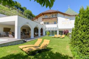 a house with a yard with lounge chairs in front of it at Sonnenhotel Adler Spa & Nature Adults only in Villandro