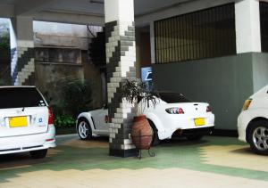 two white cars parked in front of a garage at Mc-Elly's Hotel in Arusha