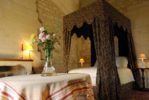 Veuil弗伊城堡住宿加早餐旅馆的卧室里有一张床，桌子上放着一瓶花