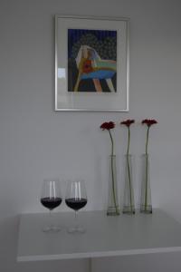 two glasses of wine and vases with flowers on a shelf at Fredensholm Annex in Skanderborg