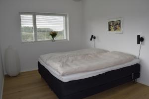 a bed in a white room with a window at Fredensholm Annex in Skanderborg