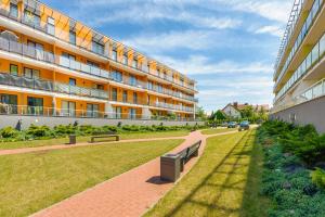 a building with two benches in front of it at Apartamenty Sun & Snow Osiedle Pogodne in Kołobrzeg