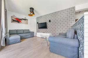 salon z 2 niebieskimi kanapami i telewizorem w obiekcie Apartamenty Sun & Snow Osiedle Pogodne w Kołobrzegu