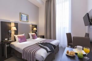 a hotel room with a bed and a table with a plate of food at Odalys City Dijon Les Cordeliers in Dijon