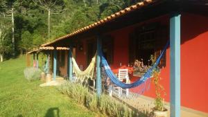 a red house with hammocks on the side of it at POUSADA ESTAÇÃO MARMELO in Queimada