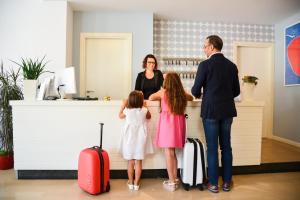 Un homme, une femme et une petite fille debout au comptoir dans l'établissement Hotel Domingo, à Lido di Jesolo