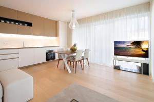 a kitchen and dining room with a table and a tv at Designed Apartment with swimming pool near the beach in Opatija