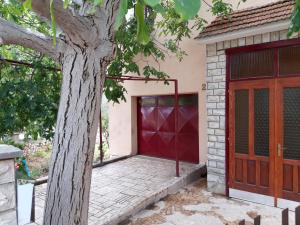 a garage with a red door next to a tree at Apartman Adriatic BnM in Biograd na Moru +7 photos