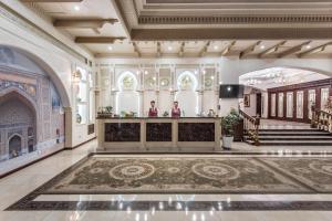 a lobby with two people standing at a counter in a building at The Royal Mezbon Hotel & SPA in Tashkent