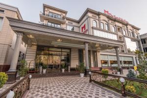 ein Geschäft vor einem Gebäude mit einer Terrasse in der Unterkunft The Royal Mezbon Hotel & SPA in Taschkent