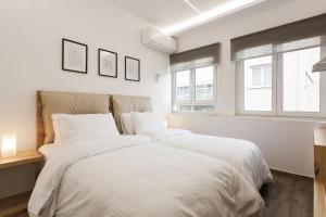 a white bedroom with a large bed with white sheets at CosmosDome. Best view in the heart of Athens! in Athens