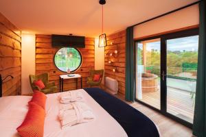 a bedroom with a large bed and a balcony at Le Hameau Des Sens in Phalsbourg