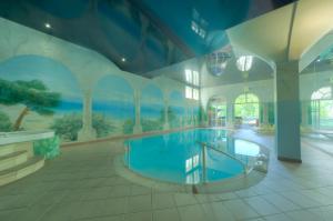 a large swimming pool in a building with a painting on the wall at Hotel Lahnschleife in Weilburg