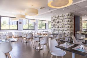 un restaurante con mesas y sillas y una pared de ventanas en Zenitude Swiss Apparthotels, en Ferney-Voltaire