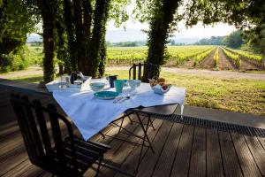einen Tisch mit einem weißen Tischtuch auf einem Deck mit einem Weinberg in der Unterkunft Château La Croix Des Pins in Mazan