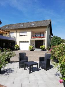 a patio with chairs and a table in front of a house at Wein-und Gästehaus Alfons Bollig in Trittenheim