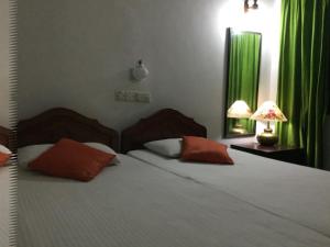 a bedroom with a large bed with red pillows and green curtains at Kandy Inn Madugalle’s family guest house in Kandy